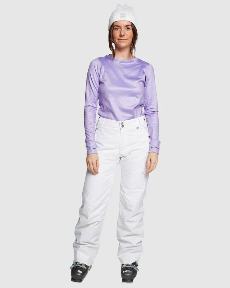 Woman wearing ROJO Adventure Awaits white snow pants, a purple long-sleeve top, and white beanie.
