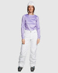 Woman wearing ROJO Adventure Awaits white snow pants, a purple long-sleeve top, and white beanie.