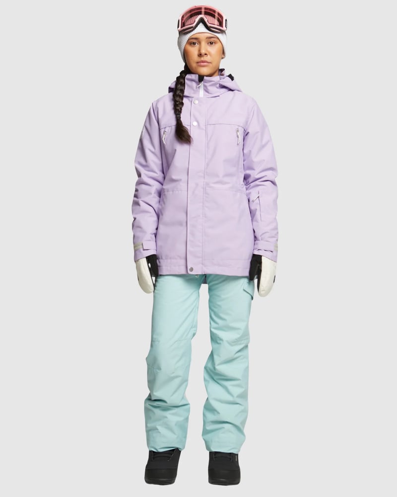 ROJO Adventure Awaits mint green snow pants worn with a lavender jacket and goggles, front view.